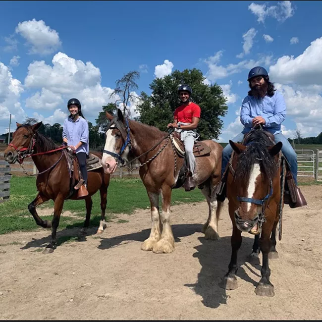 Three people on horses smiling at the camera.